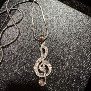 Silver necklace with treble clef note studded in cubic zirconia.